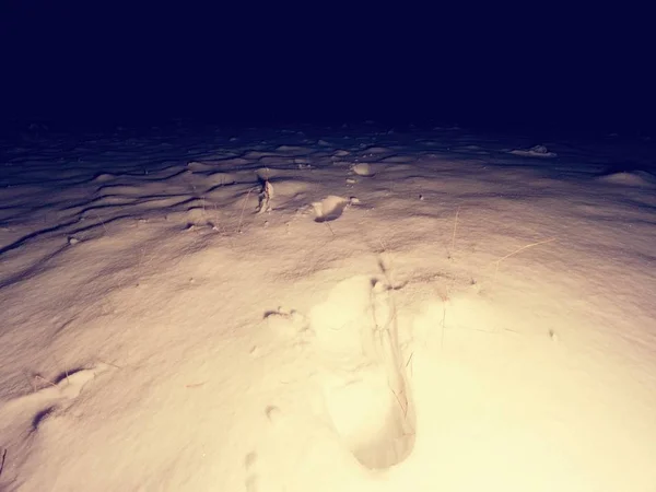 Footprints on fresh snow by night vanishing in the dark. Fear in darkness