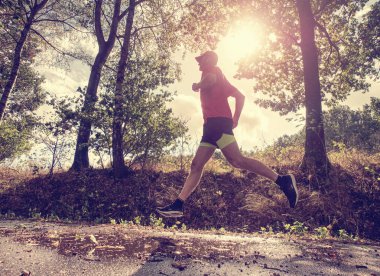 Erkek atlet açık havada parkta koşmak maratonu için eğitim sırasında atlıyor. Uygun genç spor fitness modeli açık.