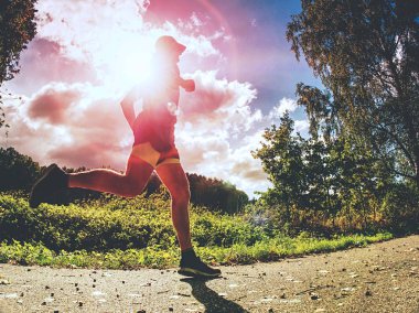 Ağaçlar gölgeler güneş siyah sarı şort ve mavi jogging kıyafetleri giyerken onu ışık ile erkekte uzun boylu spor koşu