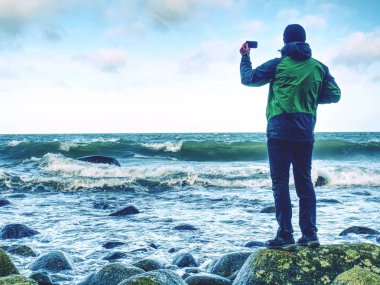 Okyanus ortasında kayada duran adam. Turist tek başına bir rock ve izlerken deniz ufuk günbatımı içinde