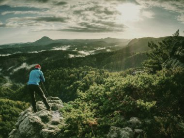 Fotoğrafçı günbatımı sırasında işyerinde silüeti. Fotoğrafçı ya da arka plan için doğal bir tripod üzerinde bir profesyonel Dslr fotoğraf makinesi kullanarak gezgin