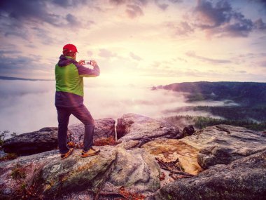 Uzun yürüyüşe çıkan kimse blogger alarak fotoğraf yanında sonbahar günbatımı dağlar manzara smartphone. Seyahat yaşam tarzı ve macera tatil paylaşımı. Açık modern teknoloji kullanın