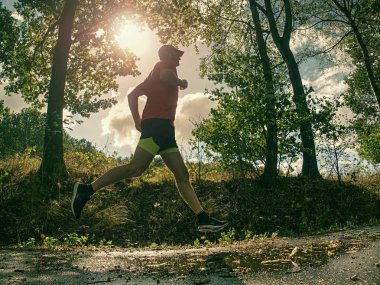 Sporcu adam çalıştıran. Erkek atlet açık havada için maraton koşmak eğitim sırasında Sprint. Atletik uygun genç spor fitness modeli, dışarıda Sonbahar Doğa ıslak yol.