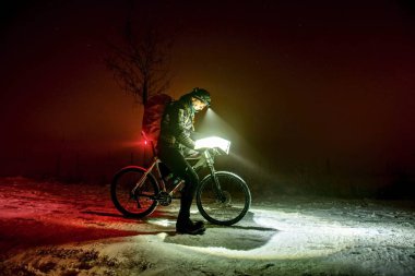 Aşırı kış mtb yarış. Kış bisiklet bisikletçi adam karda kalır ve far altında kağıt harita kontrol edin. Kış aşırı spor, sportif kavram.