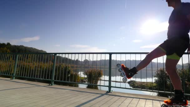 夏にローラー スケートでスポーツマン 湖の道の上でスケートをインライン展開できます 太陽に反対運動 — ストック動画