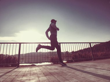 Adam onun arkasında güneş ile doğada eğitiyor. Genç adam açık havada çalıştırmak sabahı.