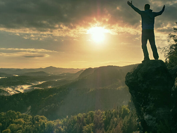 Crazy man at edge. Fearless hiker on cliff above deep hole. Morning or evening Sun close to horizon. Pure nature landscape