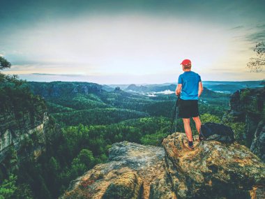 Tripod üzerinde cliff ve düşünme ile profesyonel fotoğrafçı. Rüya gibi manzara gündoğumu içinde. Güzel saf doğa aşağıdaki