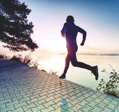 Lake shore kaldırımda gündoğumu veya günbatımı - sağlıklı yaşam konsepti sırasında koşan adam