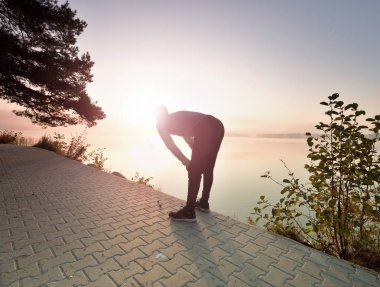 Orta runner dur nefes için yaşlı. Sporcu bir mola alır ve sabah güneş ufuk üzerinde seyir
