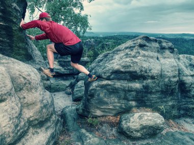 Runner pembe ceket ve ışık siyah şort. Kısa kızıl saçlı adam rocky Dağları'nda yolda.