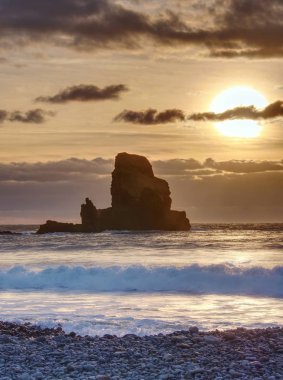 Keskin siluetleri ve yuvarlak kayalar pürüzsüz denizden çıkmış. Rüzgarsız denizde akşam içinde mavi atmosfer. 