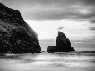 Rüzgarsız denizde akşam içinde mavi bir atmosfer. Pürüzsüz denizden çıkmış büyük yuvarlak kayalar.