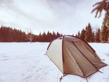 Kar altında yürüyüş çadır ile manzara. Yeşil çadır ve sabah ışık donmuş gölün yüzeyinde