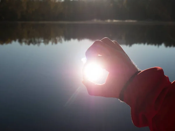 手伸向湖面上的太阳 透过折叠的手指看日落 — 图库照片
