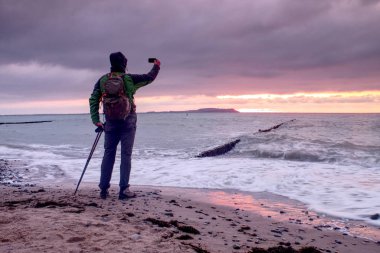 Adam fotoğrafçı silüeti almak güzel günbatımı gökyüzü ile offshore sonbahar fotoğrafı
