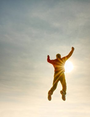 Uçan adam. Adam ve günbatımı gökyüzü atlama siluet. Güneş parlaması