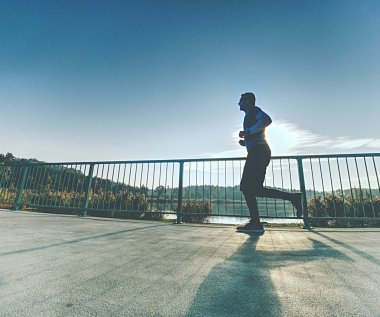 Çekici sırım gibi adam Güneş'e karşı koşu. Düzenli sabah deniz eğitim. Genç sporcunun koşu