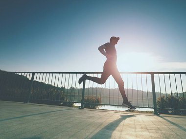 Sportif adam köprüyü havaya çalıştırın. Spor ve yaşam tarzı kavramı - şehir Köprüsü üzerinde koşan ince adam. Açık havada çalışma runner