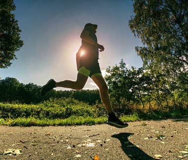 İnce gövde adam yolu düşen yapraklar ile çalışır. Sıcak gün açık excersising için. 