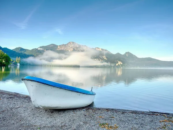 明るい日当たりの良い夏の日に湖と周辺の緑の自然の美しい風景の背景の海岸にボートを釣り — ストック写真