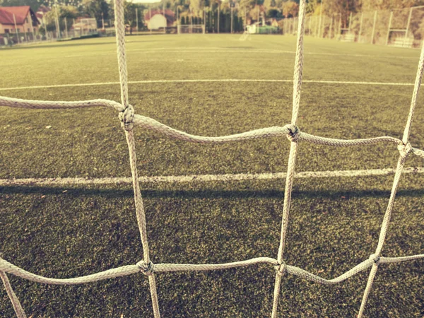 Soccer or football corner lines through safety net. View from behind the tribune net with blurred stadium and field pitch