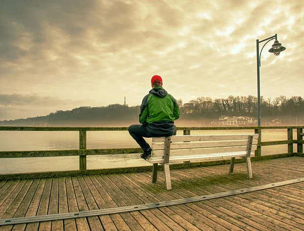 地平線を見て海橋のベンチに坐っていた男 — ストック写真
