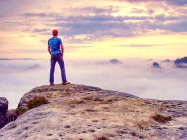 Açık havada duran ve elleri cebinde tutmak sporcu. Gündoğumu kendi keyif alıyor. Uzun yürüyüşe çıkan kimse karşı bulutlar parlama ile buzlu