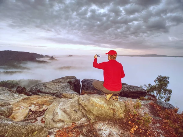 Courageous Man Sitting Peak Rock Makes Photo His Phone Autumn — Stock Photo, Image