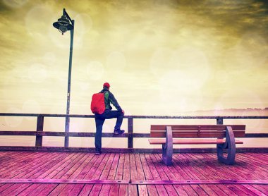 Sırt çantası deniz arka plan üzerinde ahşap iskele üzerinde turist adam. Hipster filtre. 