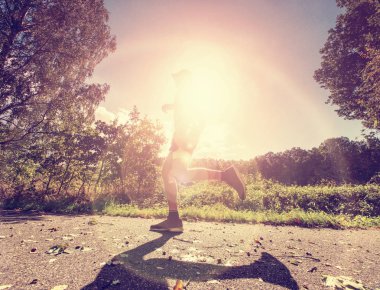 Asfalt yolda koşan adam. Arka planda yoğun ağaçları ile hızlı bir parkta çalıştıran atlet.