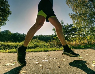 Acil beden eğitimi. Atlet sokaktan hızlı çalışır. Düşen akçaağaç ve resul yapraklar ile Asfalt ıslak