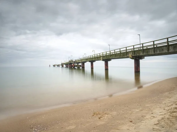 Shallow sea with a rising sea bridge. The pier leaving far into the sea
