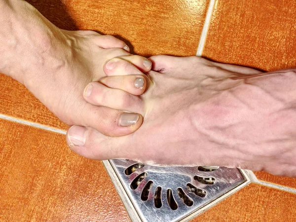 Female and male feet of together washing bodies in shower room. Feet on red tilles selective focus on toes