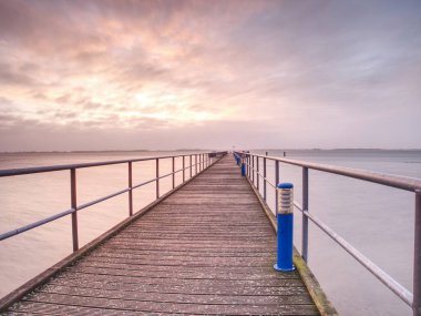 Boş rıhtım, sakin deniz ve gökyüzü arka plan. Pürüzsüz okyanus üzerinde ahşap köprü görünümünü. İskeledeki ahşap iskele bakış