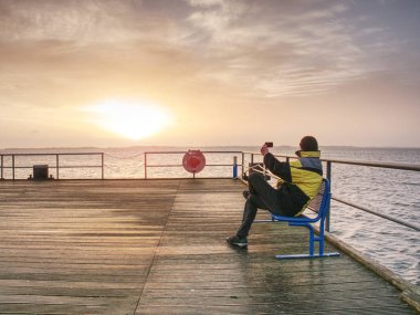 İskele inşaat ve fotoğraf sabah deniz adamı. Yumuşak su seviyesinden akıllı telefon ile turizm