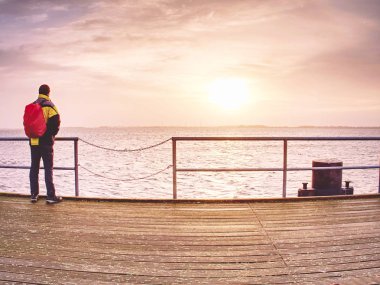 Deniz üstünde ahşap iskele sonbahar buğu adam turist. Depresyon karanlık atmosfer. 