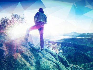 Soyut, üzerinde filtre. Yalnız adam kayalarda gündoğumu manzarasına sahip. Genç erkek kişi uçurumun kenarında duruyor 