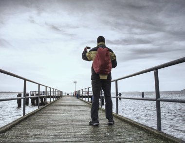 Turist adam akıllı telefonu ile deniz fotoğraf çekiyorum. Mobil sokak fotoğrafçılığı yolculuğu. Elleri ve cep telefonu üzerinde odaklanmak.