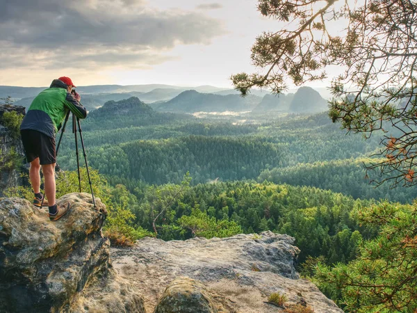 Photographer or videographer  traveler with heavy backpack and tripod in hand is preparing for art work. Artist in pure nature take impressive landscape photos.