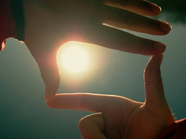 El tarih Pzr. Güneş tutan el silüeti. Güneş su seviyesinden düşük. Güzel gölge oyunu.