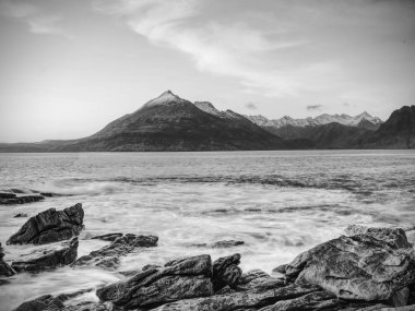 Taşlık Plajı ve rocky Bay cliff. Şubat gün batımı, pembe ufuk mavi tonlarını. Karanlık slipery kayalar derin çatlaklar.