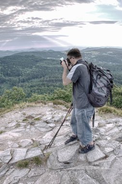Kamerasını tutan bakış açısı üzerinde uzun boylu genç adam. Fotoğrafçı alarak resmi orman, gökyüzü ve bulutlar onun tatil. Adam seyahat tek başına