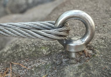 Cliff kayaya bağlı kemer tırmanma. Paslanmaz demir çubuk üzerinde dağ üst sığ derinlik-in tarla bağlı ferrata çelik kablo ile detay.