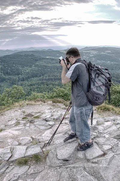 Kamerasını tutan bakış açısı üzerinde uzun boylu genç adam. Fotoğrafçı alarak resmi orman, gökyüzü ve bulutlar onun tatil. Adam seyahat tek başına