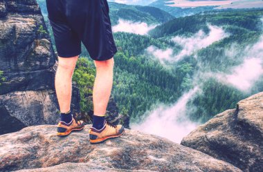 Uzun yürüyüşe çıkan kimse bacaklar üzerinde gündoğumu dağ tepe kaya tırmanışı. İnce bacakları maruz kayada yürüyüş ayakkabıları ile bir dağ uzun yürüyüşe çıkan kimse.