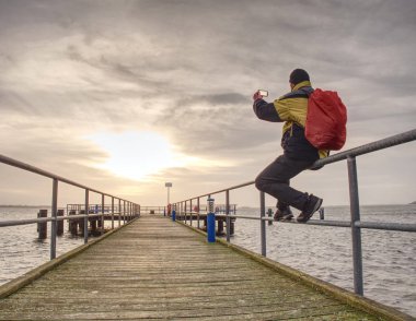 Turist adam akıllı telefonu ile deniz fotoğraf çekiyorum. Mobil sokak fotoğrafçılığı yolculuğu. Elleri ve cep telefonu üzerinde odaklanmak.