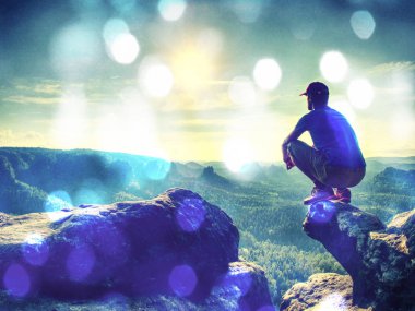 Adam uzun yürüyüşe çıkan kimse dağda bir kayanın üzerine oturmuş. Soyut, üzerinde filtre. Adam sit. Sonbahar dağ sis. Vadilerde sis