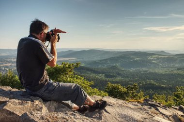 Kamerasını tutan bakış açısı üzerinde uzun boylu genç adam. Fotoğrafçı alarak resmi orman, gökyüzü ve bulutlar onun tatil. Adam seyahat tek başına