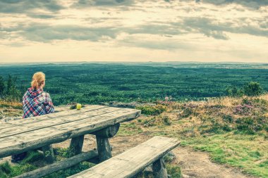 Genç gülümseyen sarışın kız trekker tahta masada peyzaj içine muhteşem manzaralı dinlenme. Oturarak ve zammı bir mola yorgun fiyatı. 